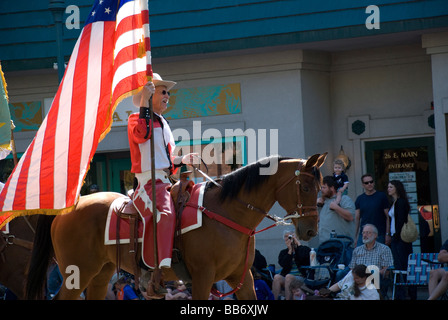 Cowboy zu Pferd mit einer amerikanischen Flagge in einer Kleinstadt-parade Stockfoto