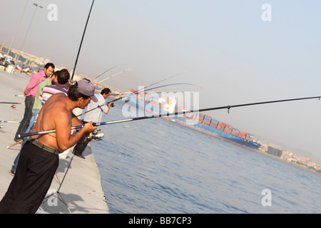 Istanbul Türkei Männer Angeln am Meer in Kumkapi mit großen Containerschiff Schiff hinter den Bosporus verlassen Stockfoto