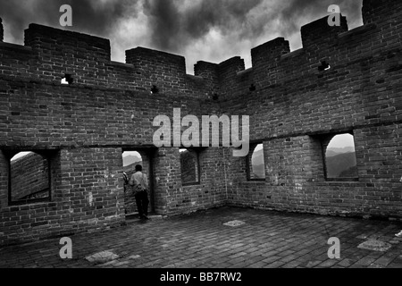 Ein Mann steht in einem Wachturm auf der großen Mauer bei Jinshanling, nördlich von Peking, Volksrepublik China. Stockfoto