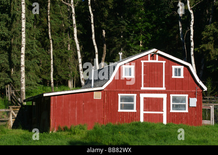 Kleine rote und weiße Scheune in einer bewaldeten Landschaft Stockfoto