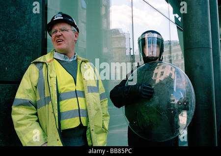 Ein Polizist neben einem Handwerker während der 2009 G20-Gipfel Protest in London Stockfoto