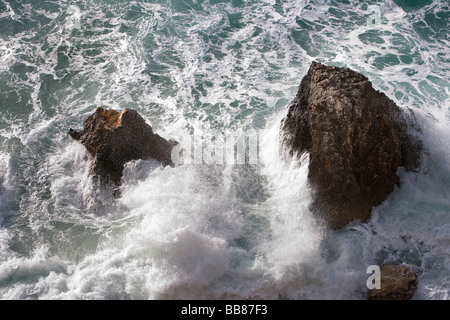Wellen gegen Felsen Stockfoto