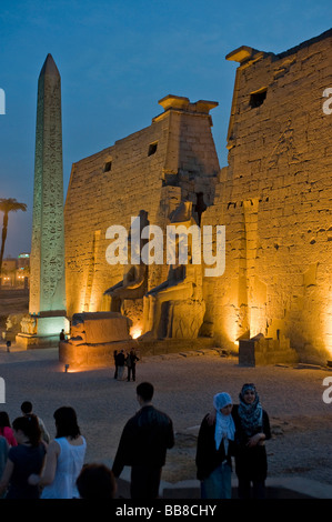 Pylon mit Figuren und Obelisk Ramses II beleuchtet am Abend vor einem Minarett, Luxor-Tempel, Luxor, Ägypten, Af Stockfoto