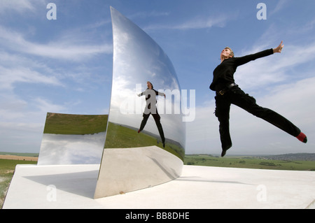 Festival Guide Helen Goodwin springt vor C-Kurve die riesige konkave Edelstahl Spiegelinstallation von Anish Kapoor Stockfoto