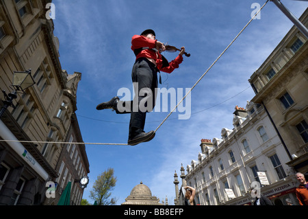 A Street Theatre Straßenmusiker spielt auf einer Violine beim Balancieren auf einem Drahtseil in Brighton Festival Stockfoto