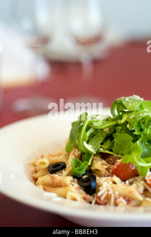 Eine Platte mit einer Mahlzeit Nudeln Oliven Tomaten Käse und Rucola Stockfoto