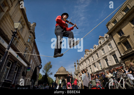 A Street Theatre Straßenmusiker spielt auf einer Violine beim Balancieren auf einem Drahtseil in Brighton Festival Stockfoto