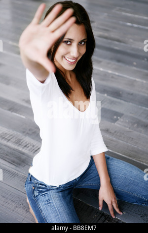 Porträt der jungen knienden schöne Frau Streching Hand lächelnd Stockfoto
