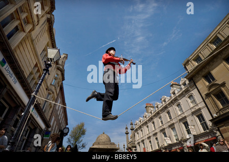 A Street Theatre Straßenmusiker spielt auf einer Violine beim Balancieren auf einem Drahtseil in Brighton Festival Stockfoto