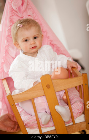 Junges Mädchen, 1 Jahr alt, sitzt in seiner Puppe Kinderwagen Stockfoto