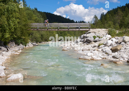 Mountainbike-Reiterin über eine schmale Holzbrücke über die Leutascher Ache, Gaistal, Leutasch, Tirol, Österreich, Stockfoto