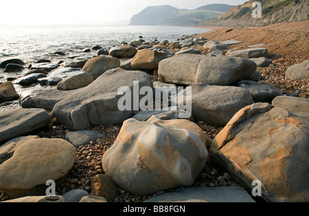 Klar, Meer Wasser wirbeln um Felsen und Kieselsteine am Strand von Charmouth Stockfoto