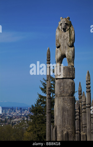 Tragen Sie Totem auf dem "Spielplatz der Götter" in Burnaby Park mit Vancouver, British Columbia, Kanada, im Hintergrund. Stockfoto