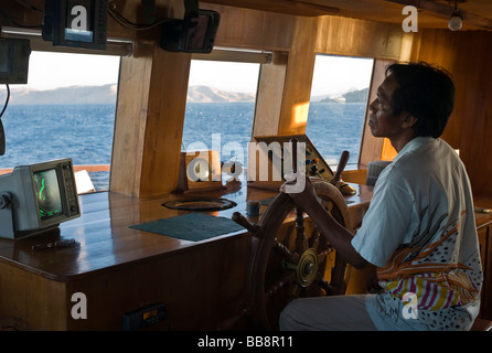 Mann am Lenkrad, Radargerät auf der Brücke eines Segelschiffes, Indonesien Stockfoto