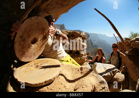 Lokale Führer zeigt Mühlsteine in dem verlassenen Dorf Sab Bani Khamis in Jebel Shams in Oman Stockfoto