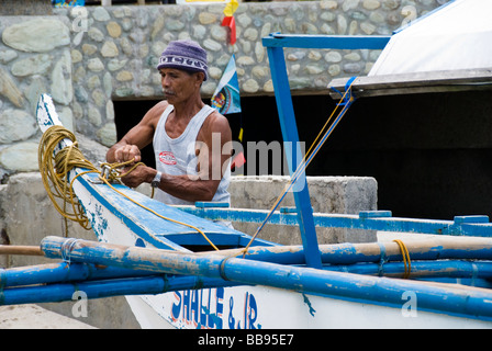 Bootsmann Vorbereitung seiner Bangka (Filipino Boot) in Puerto Galera, Philippinen Stockfoto