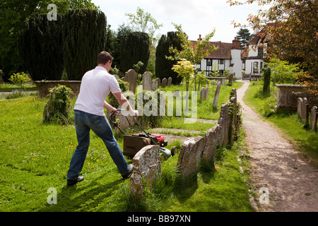 England Berkshire Cookham heilige Dreiheit Pfarrkirche Friedhof Mann Friedhof Rasenmähen mit Rasenmäher Stockfoto