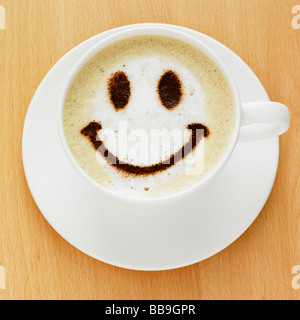 Eine Tasse Kaffee Cappuccino-Stil mit einem Smiley-Gesicht auf der Oberseite in Schokoladenpulver, erschossen auf einer Tischplatte. Stockfoto