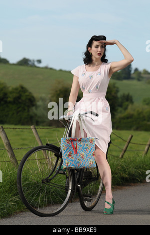 Frau trägt Vintage-Kleidung auf einem alten Fahrrad Stockfoto