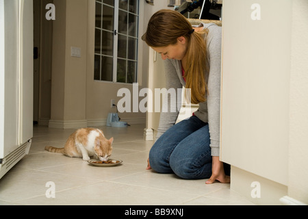 Fütterung Katze Jugendmädchen 15-16-17 Jahre alt kniend kniet auf dem Boden feeds Katze in der Küche HERR © Myrleen Pearson Stockfoto