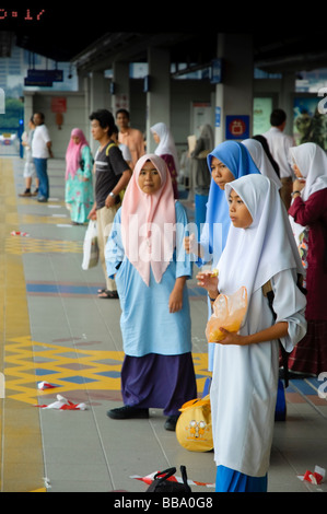 Mädchen, gekleidet in Hijab, eine tropische Frucht, während des Wartens auf einen Zug zu essen. KL Sentral Station, Kuala Lumpur, Malaysia. Stockfoto