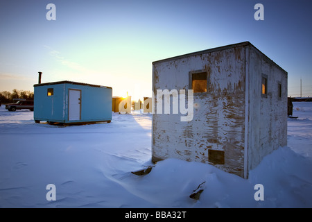 Eis-Fischerhütten auf dem gefrorenen roten Fluss bei Sonnenuntergang, in der Nähe von Selkirk, Manitoba, Kanada. Stockfoto