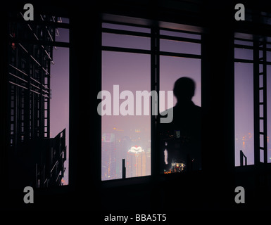 Silhouette des Mannes vor Fenster mit Blick auf die Skyline von Shanghai, China. Stockfoto