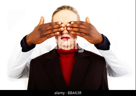 Dunkel-enthäutete Hände, die Augen eines jungen blonden Mädchens zu halten geschlossen Stockfoto