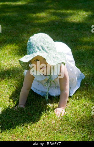 BABY MÄDCHEN KLEINKIND BEI SONNENHUT GENIEßEN SIE SONNENSCHEIN UND BLUMEN IN EINEN ENGLISCHEN GARTEN. Stockfoto