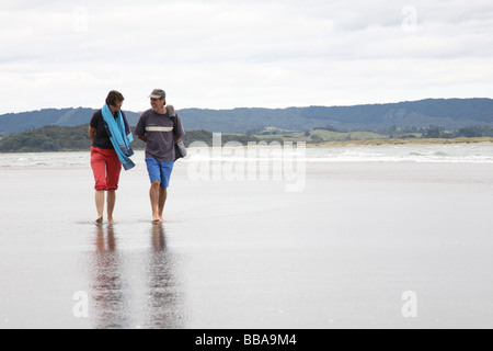 Paar am Strand entlang spazieren Stockfoto