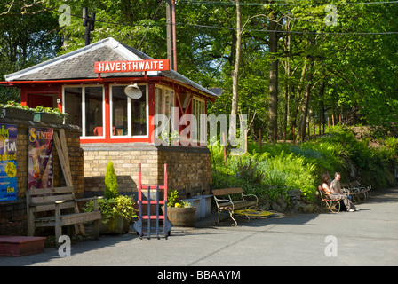 Zwei Personen Standortwahl auf Bank im Haverthwaite Bahnhof an der Lakeside & Haverthwaite Railway, South Lakeland, Cumbria, England UK Stockfoto