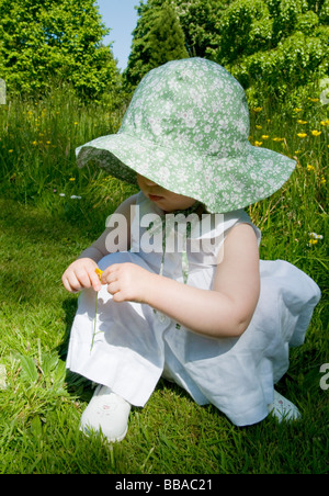 BABY MÄDCHEN KLEINKIND BEI SONNENHUT GENIEßEN SIE SONNENSCHEIN UND BLUMEN IN EINEN ENGLISCHEN GARTEN. Stockfoto