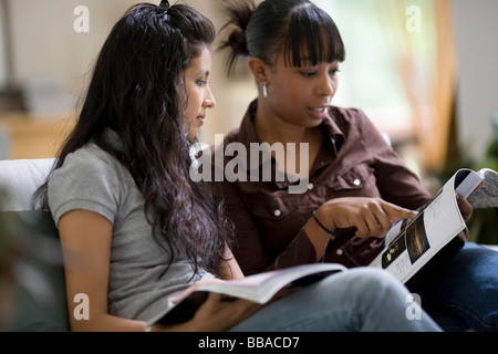 Zwei junge Frau betrachten Zeitschriften auf einem sofa Stockfoto