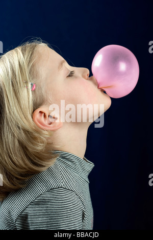 Ein junges Mädchen bläst eine Kaugummi-Blase Stockfoto