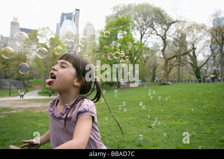 Ein junges Mädchen fangen Luftblasen im Central Park in New York City Stockfoto