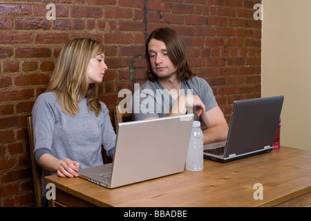 Ein junges Paar sitzen nebeneinander mit Notebooks Stockfoto