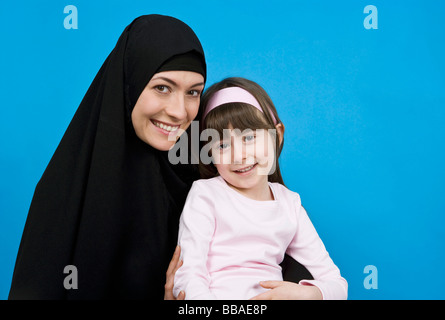 Eine Frau trägt ein Kopftuch und ihre Tochter auf dem Schoß hielt Stockfoto