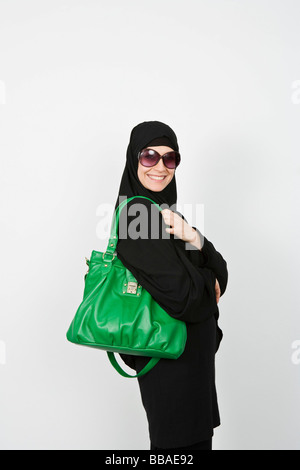 Porträt einer Frau trägt ein Kopftuch, Sonnenbrille und eine Geldbörse Stockfoto