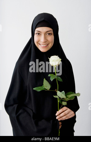 Porträt einer Frau ein Kopftuch trägt und hält eine rose Stockfoto
