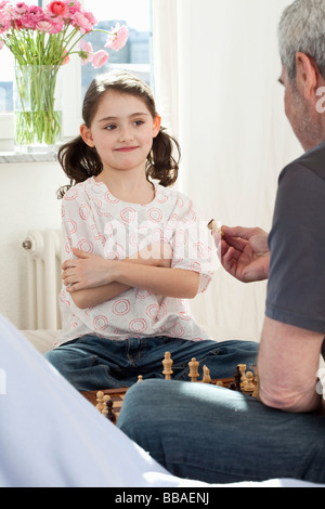 Ein Mädchen und ihr Großvater Schach spielen Stockfoto