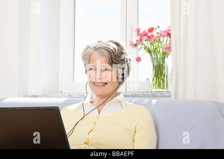 Eine Frau mit einem Laptop und Kopfhörer anhören Stockfoto