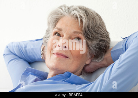 Eine ältere Frau entspannend mit ihren Händen hinter dem Kopf Stockfoto