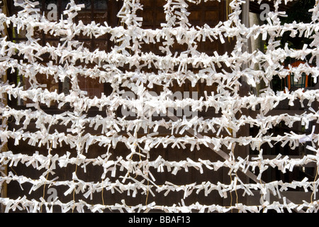 Nahaufnahme von Tausenden von Pech-O-mikuji, Omikuji, Glücksritzen aus weißem Papier, die an parallele Stiche gebunden sind und am Yasaka-Schrein in Kyoto ein Muster bilden. Stockfoto