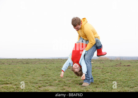 Ein Mann hält ein Junge auf dem Kopf stehend in einem park Stockfoto