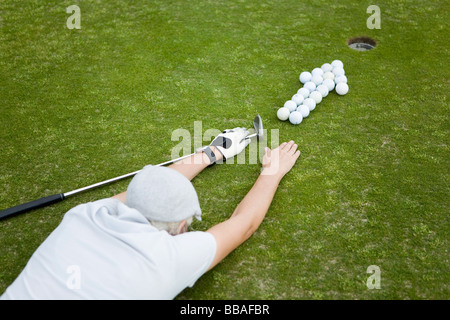 Ein Golfer auf ein Putting Green liegt hinter einem Pfeil von Golfbällen Stockfoto