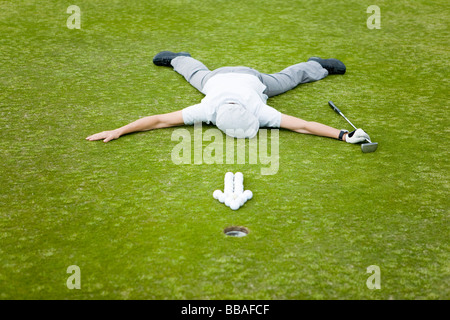 Ein Golfer auf ein Putting Green liegt hinter einem Pfeil von Golfbällen Stockfoto