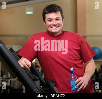 Mann an laufenden Maschinen im Fitnessraum entspannen Stockfoto