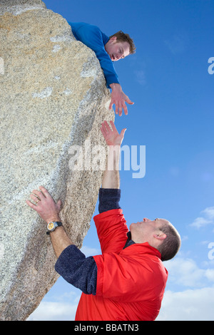 Kletterer, die anderen Bergsteiger Hand anzubieten Stockfoto