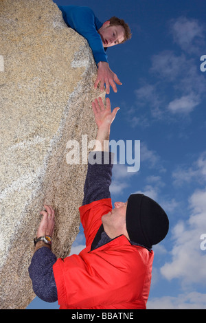Kletterer, die anderen Bergsteiger Hand anzubieten Stockfoto