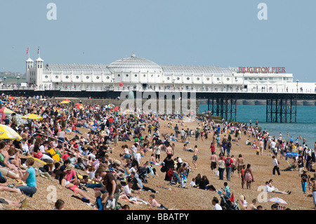 Massen von Urlaubern am Strand von Brighton mit dem Pier im Hintergrund. Stockfoto